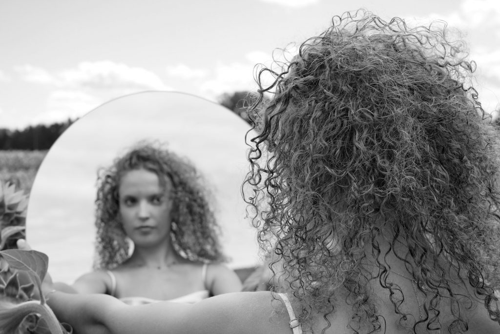 a woman with curly hair looking in a mirror
